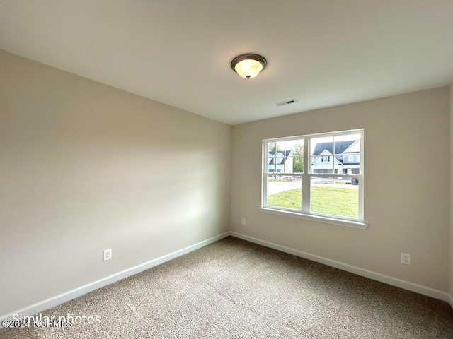 spare room with carpet, visible vents, and baseboards