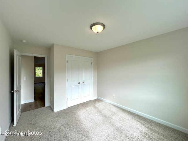 unfurnished bedroom with carpet floors, a closet, and baseboards