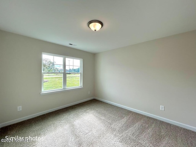 unfurnished room with carpet floors, visible vents, and baseboards