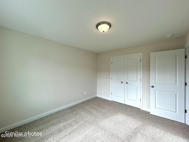 unfurnished bedroom with carpet floors, a closet, and baseboards