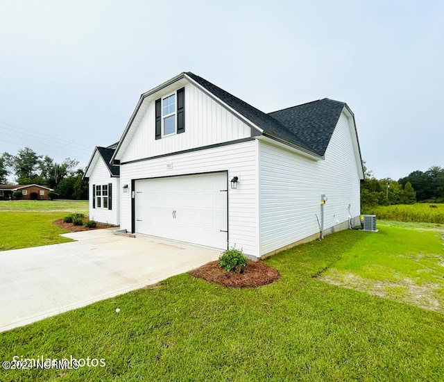 view of side of home with concrete driveway, roof with shingles, an attached garage, a yard, and board and batten siding