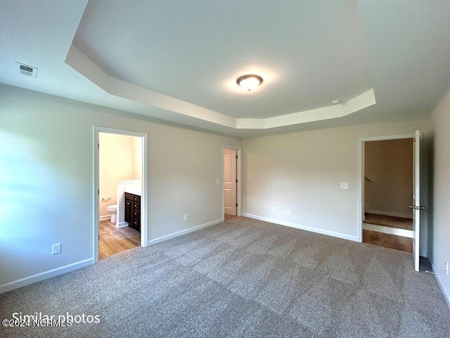 unfurnished bedroom featuring carpet floors, a raised ceiling, visible vents, and baseboards