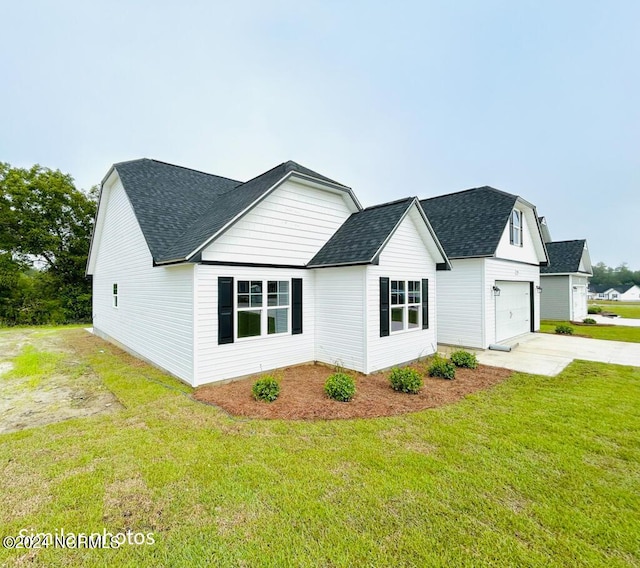 view of front facade with a garage, concrete driveway, a front lawn, and roof with shingles