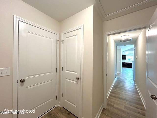 corridor featuring visible vents, baseboards, and dark wood finished floors