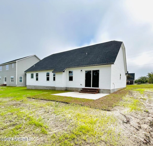 rear view of property featuring entry steps, roof with shingles, a patio, and a lawn