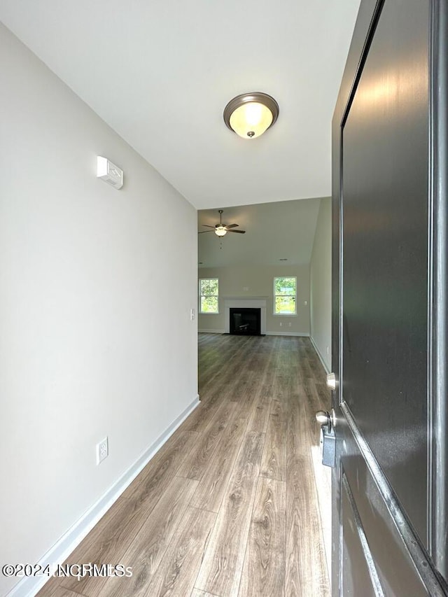 unfurnished living room featuring light wood-style floors, a fireplace, baseboards, and a ceiling fan