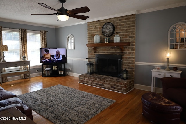 living area featuring a textured ceiling, crown molding, a fireplace, and wood finished floors