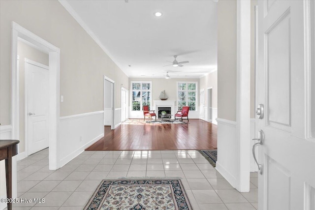 entrance foyer featuring light tile patterned floors, ceiling fan, and a fireplace