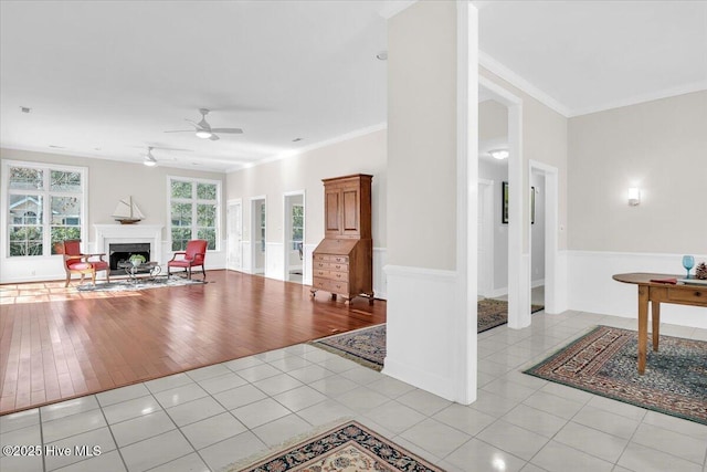 tiled living room featuring ceiling fan, ornamental molding, and a fireplace