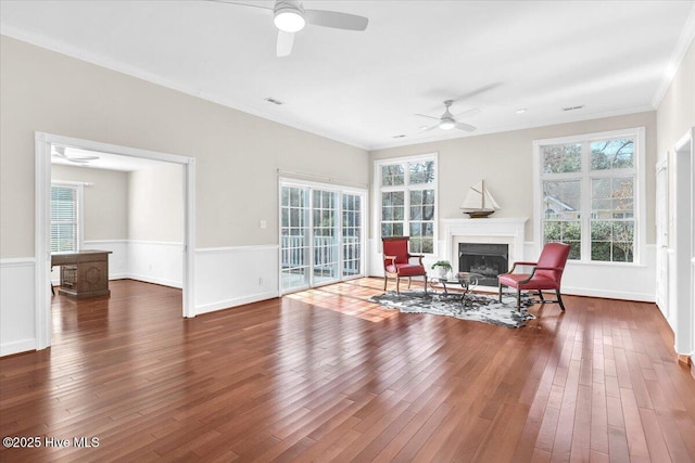 sitting room featuring a fireplace, hardwood / wood-style floors, ornamental molding, ceiling fan, and baseboards