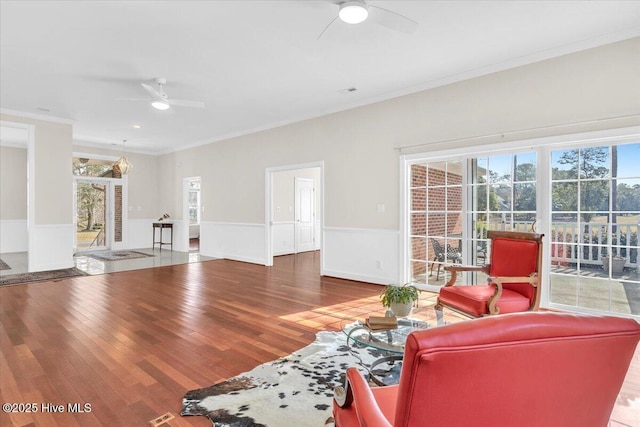 living room featuring wood finished floors, a ceiling fan, and crown molding