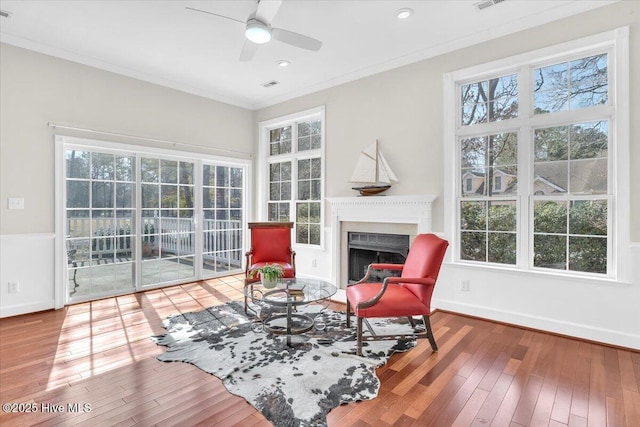 sitting room featuring baseboards, ornamental molding, hardwood / wood-style floors, and a healthy amount of sunlight