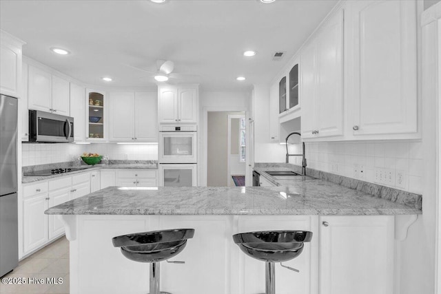 kitchen with stainless steel appliances, white cabinets, a sink, and a peninsula