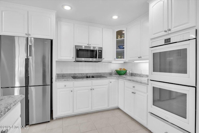 kitchen featuring light stone counters, appliances with stainless steel finishes, and glass insert cabinets