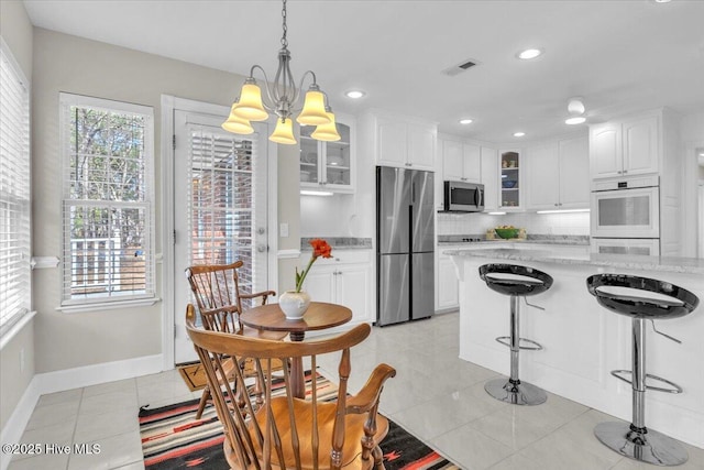 kitchen featuring light tile patterned floors, visible vents, white cabinets, appliances with stainless steel finishes, and glass insert cabinets