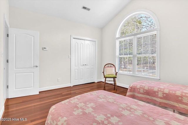 bedroom with lofted ceiling, wood finished floors, visible vents, and baseboards