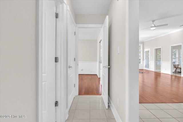 hall with ornamental molding and light tile patterned floors