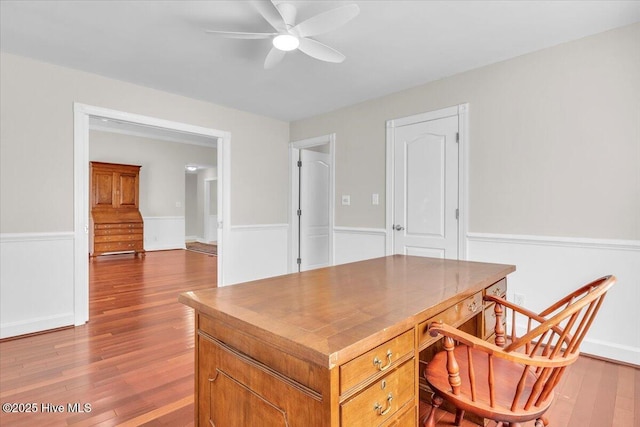 office area featuring a ceiling fan, a wainscoted wall, and wood finished floors