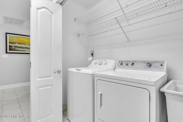 clothes washing area featuring visible vents, a sink, laundry area, independent washer and dryer, and baseboards