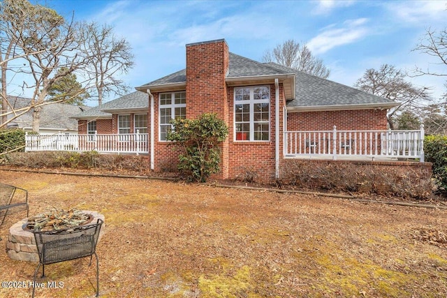 view of property exterior featuring a shingled roof, brick siding, and a chimney