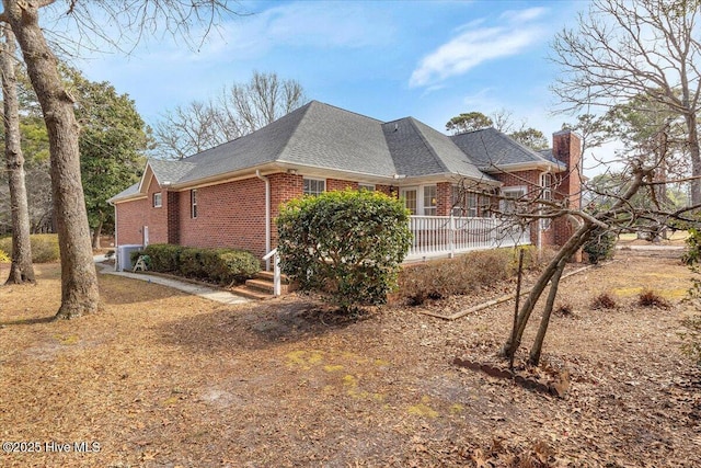 view of property exterior featuring brick siding, a chimney, and roof with shingles