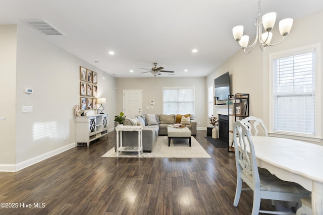 living room with dark wood-style floors, a wealth of natural light, a fireplace with flush hearth, and visible vents