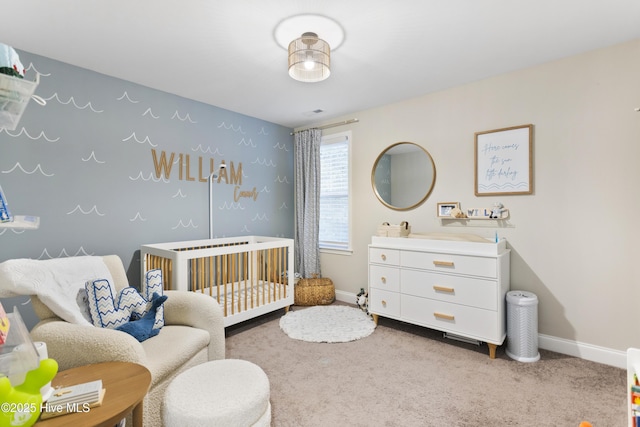 carpeted bedroom featuring a nursery area and baseboards