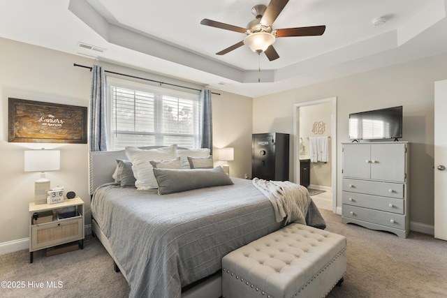 bedroom with baseboards, a raised ceiling, visible vents, and light colored carpet