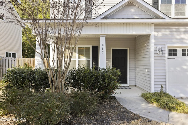 property entrance with covered porch and fence