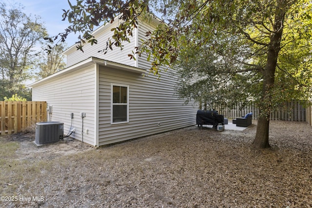 view of property exterior featuring fence, an outdoor living space, and central AC