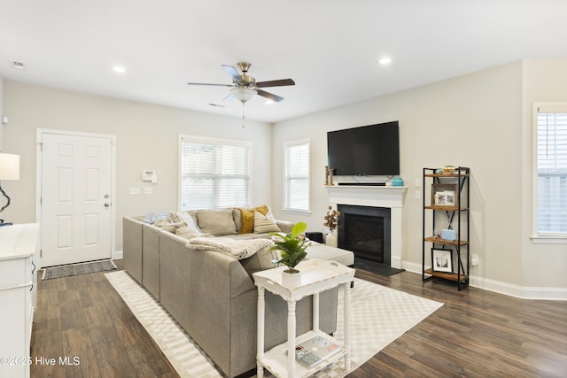 living area featuring baseboards, a glass covered fireplace, dark wood-style flooring, and recessed lighting