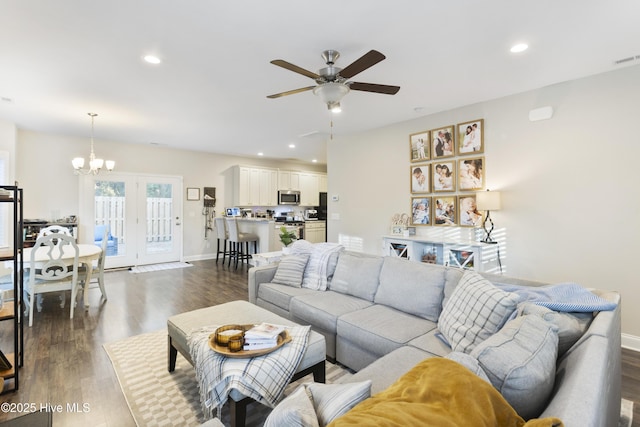 living room featuring recessed lighting, dark wood finished floors, baseboards, and ceiling fan with notable chandelier