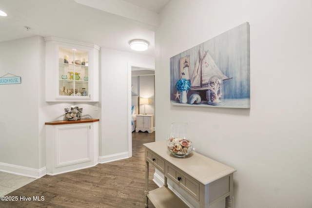 hall with baseboards and wood finished floors