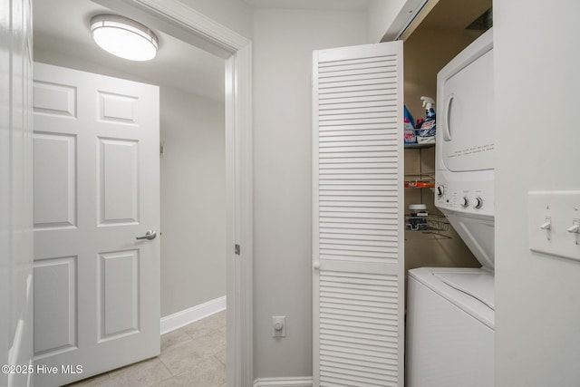 laundry area with stacked washer / drying machine, laundry area, and baseboards