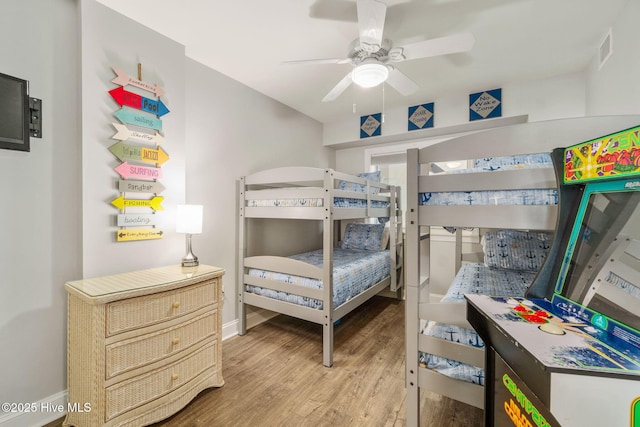 bedroom featuring a ceiling fan, baseboards, visible vents, and wood finished floors