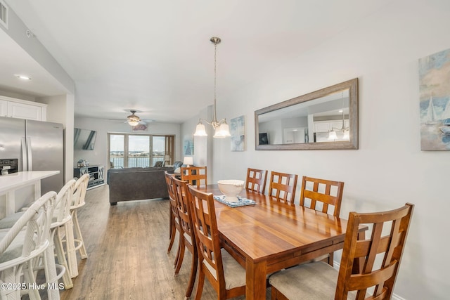 dining area featuring ceiling fan with notable chandelier and light wood-style flooring