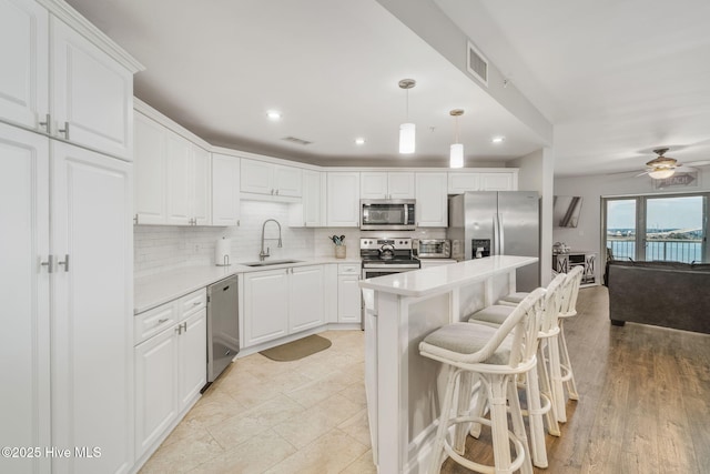 kitchen featuring a sink, white cabinetry, light countertops, appliances with stainless steel finishes, and backsplash