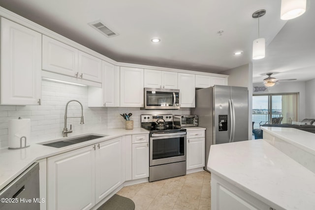 kitchen featuring tasteful backsplash, visible vents, stainless steel appliances, white cabinetry, and a sink