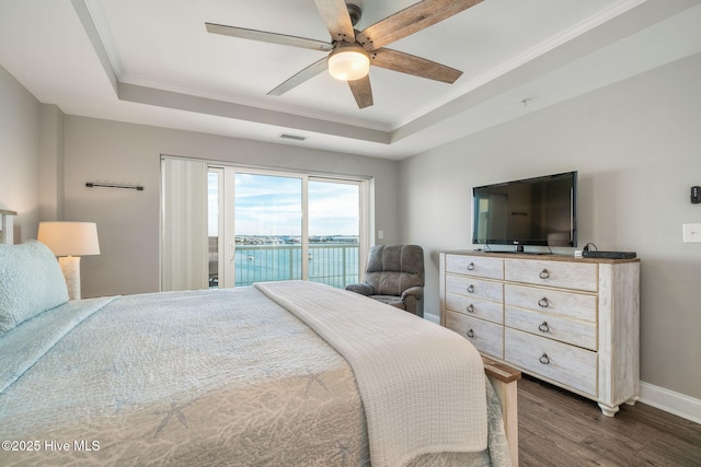 bedroom featuring ornamental molding, dark wood-type flooring, a raised ceiling, and access to exterior