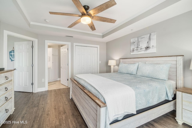 bedroom featuring visible vents, a raised ceiling, ornamental molding, wood finished floors, and a closet