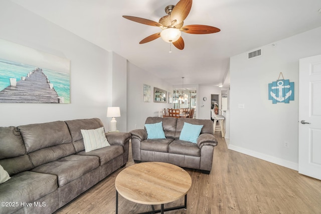 living area featuring light wood-style floors, visible vents, baseboards, and a ceiling fan