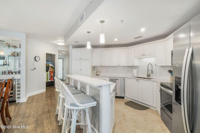 kitchen with white cabinets, tasteful backsplash, stainless steel appliances, and a sink