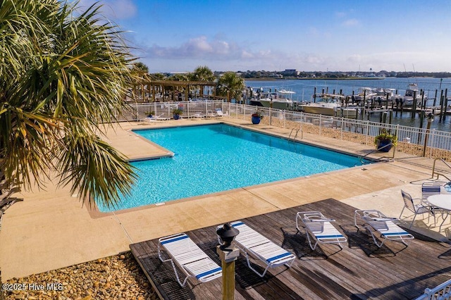 community pool with a patio, a water view, and fence