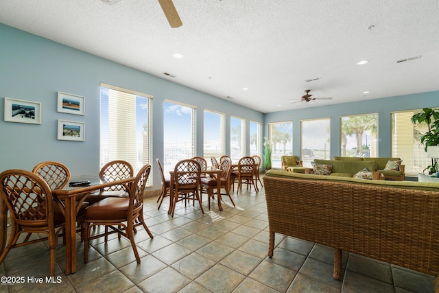 dining room with a ceiling fan, tile patterned flooring, visible vents, and a textured ceiling