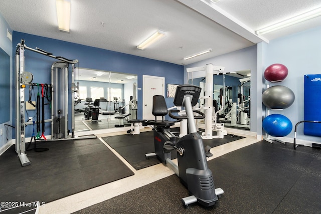 exercise room featuring a textured ceiling and baseboards