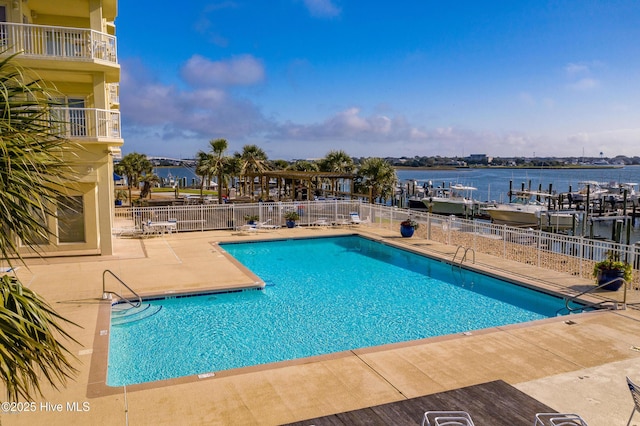 community pool featuring a water view, fence, and a patio