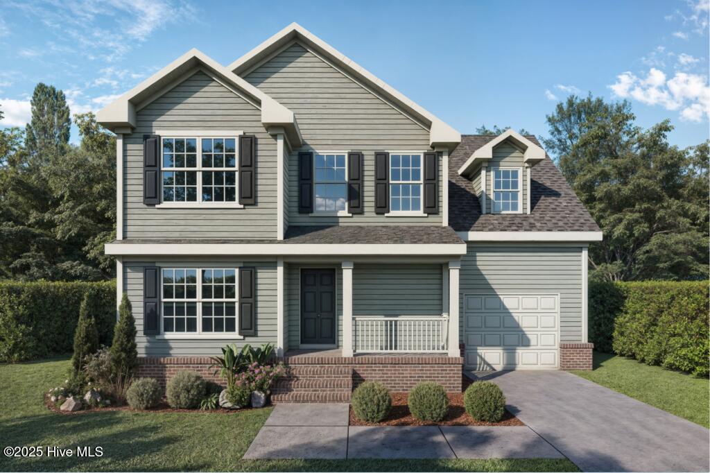 traditional-style house with a porch, a front yard, driveway, and a garage