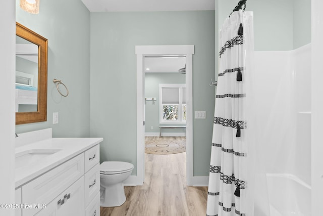 full bathroom featuring vanity, wood finished floors, baseboards, curtained shower, and toilet