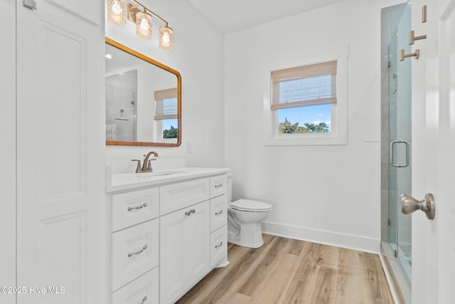 bathroom featuring vanity, wood finished floors, a stall shower, and baseboards