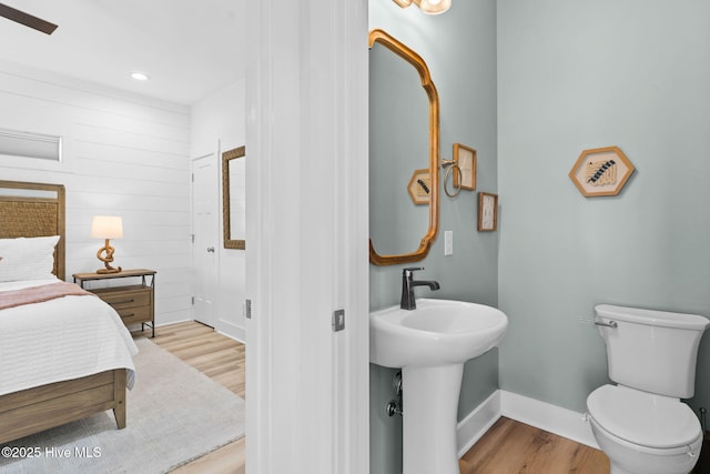 bathroom featuring toilet, wood finished floors, baseboards, and a sink